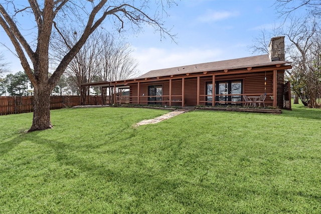 back of property with a yard, a chimney, fence, and log siding