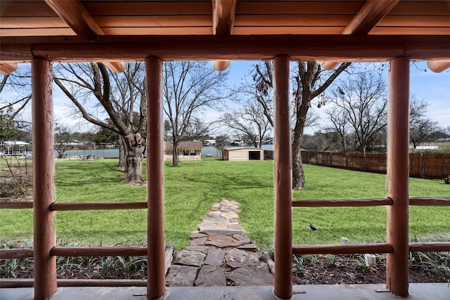 view of yard featuring a water view, fence, and an outbuilding