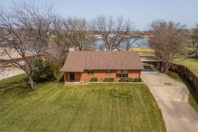 view of front facade featuring roof with shingles, fence, a front lawn, concrete driveway, and a water view