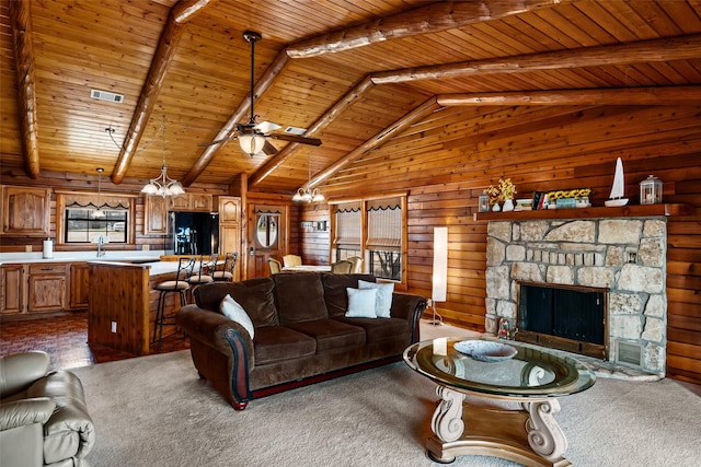 living room with visible vents, wood walls, a stone fireplace, wood ceiling, and ceiling fan with notable chandelier