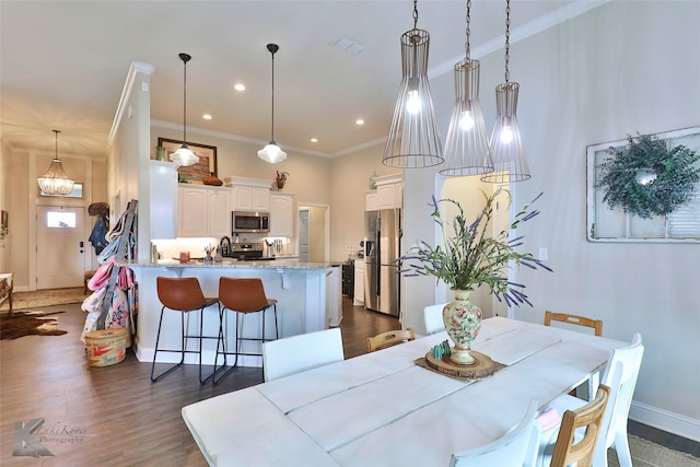 dining space with dark wood-style floors, baseboards, ornamental molding, and an inviting chandelier