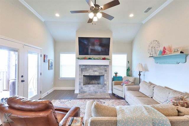 living room with a fireplace, wood finished floors, visible vents, baseboards, and crown molding