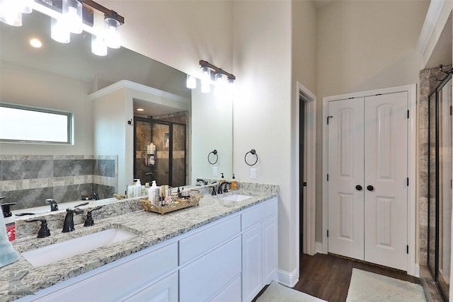 full bathroom featuring double vanity, wood finished floors, a stall shower, and a sink