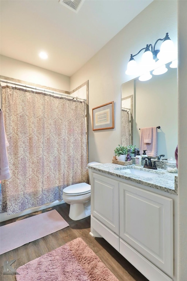 full bath with curtained shower, toilet, wood finished floors, visible vents, and vanity