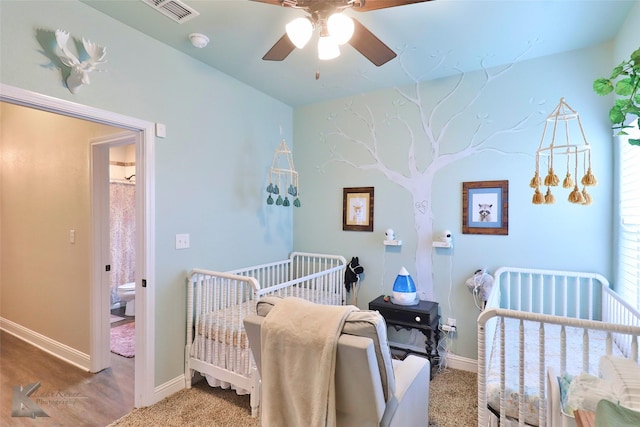 bedroom featuring a crib, a ceiling fan, visible vents, and baseboards