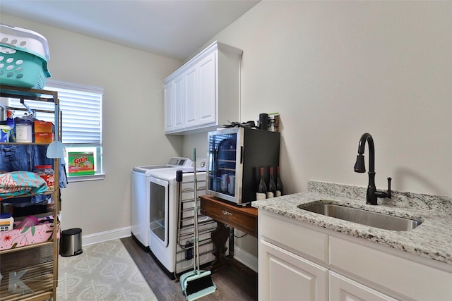 laundry room featuring cabinet space, baseboards, dark wood-style floors, independent washer and dryer, and a sink