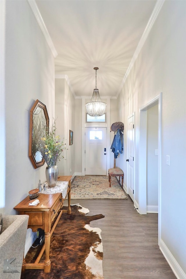 doorway to outside with a notable chandelier, crown molding, baseboards, and wood finished floors