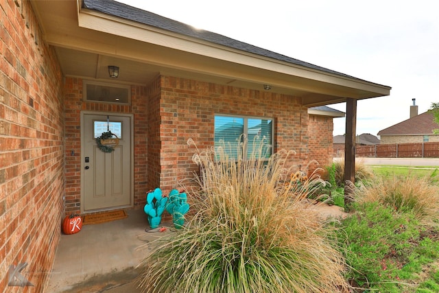 entrance to property with brick siding and fence