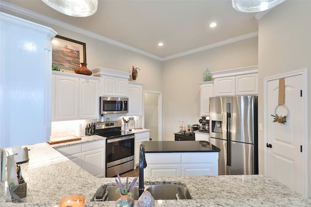 kitchen with stainless steel appliances, ornamental molding, a sink, and white cabinetry