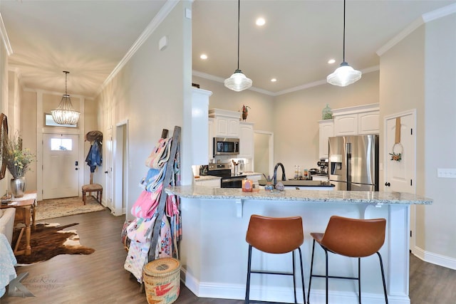 kitchen with stainless steel appliances, white cabinetry, ornamental molding, and a kitchen breakfast bar