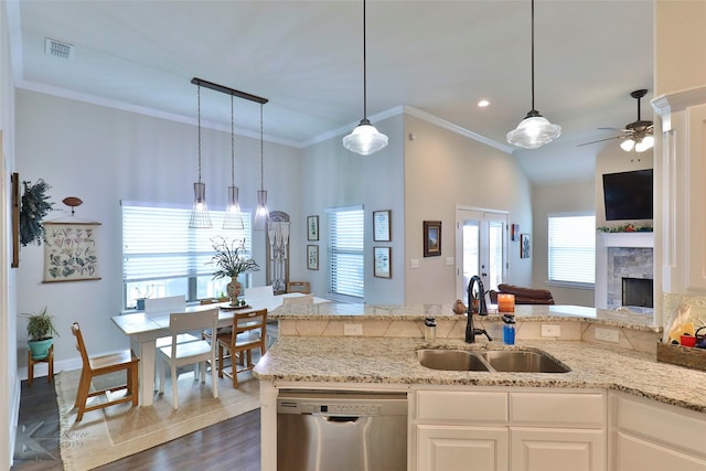 kitchen with a fireplace, a sink, light stone countertops, dishwasher, and crown molding