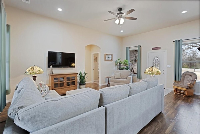 living area featuring dark wood-style floors, arched walkways, recessed lighting, a ceiling fan, and baseboards