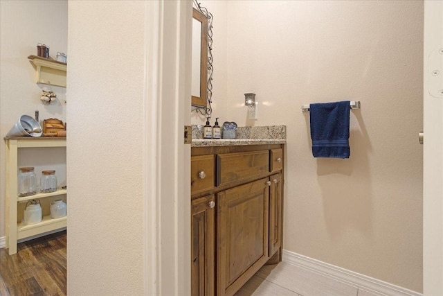 bathroom featuring vanity, baseboards, and wood finished floors