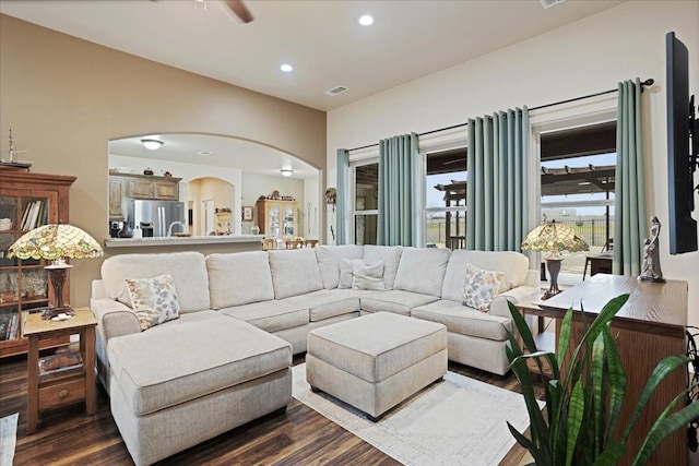 living area with arched walkways, ceiling fan, recessed lighting, visible vents, and dark wood-style floors