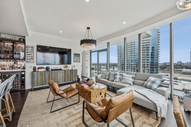 living room featuring a dry bar, recessed lighting, a chandelier, wood finished floors, and a wall of windows