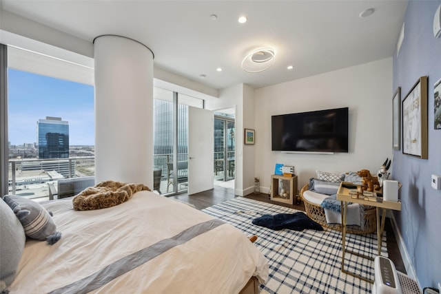 bedroom featuring recessed lighting, wood finished floors, access to exterior, baseboards, and a view of city