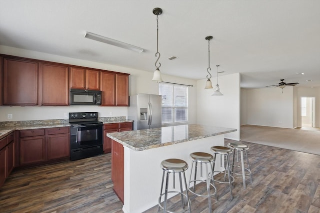 kitchen with dark wood-style floors, a center island, decorative light fixtures, a breakfast bar area, and black appliances