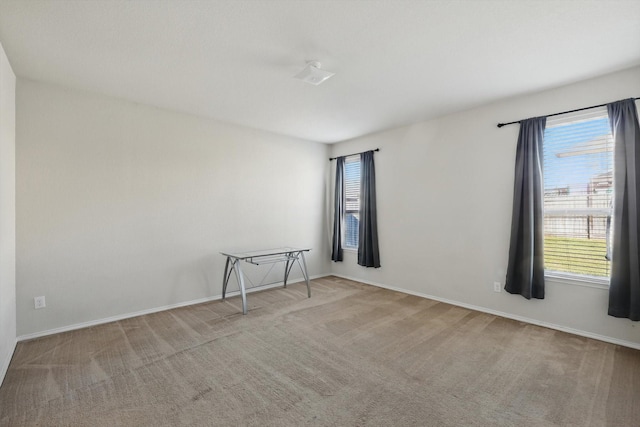 spare room featuring carpet, plenty of natural light, and baseboards