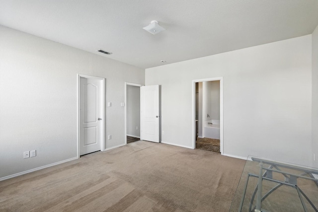 unfurnished bedroom featuring ensuite bathroom, carpet flooring, visible vents, and baseboards