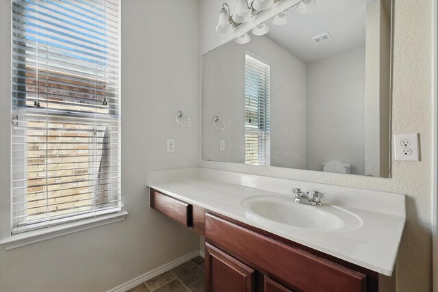 bathroom featuring visible vents, vanity, baseboards, and tile patterned floors