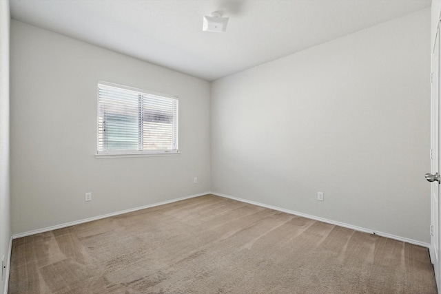 carpeted empty room featuring baseboards