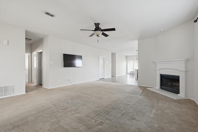 unfurnished living room featuring a ceiling fan, carpet, visible vents, and a fireplace with raised hearth