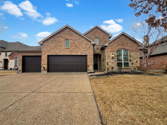 view of front of home with an attached garage, brick siding, concrete driveway, stone siding, and a front lawn