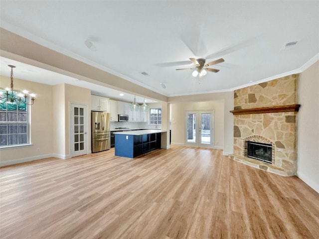 unfurnished living room featuring light wood-style flooring, a fireplace, ornamental molding, and french doors