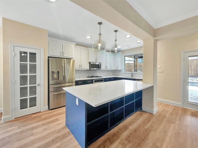 kitchen featuring light wood-style flooring, white cabinetry, light countertops, appliances with stainless steel finishes, and backsplash