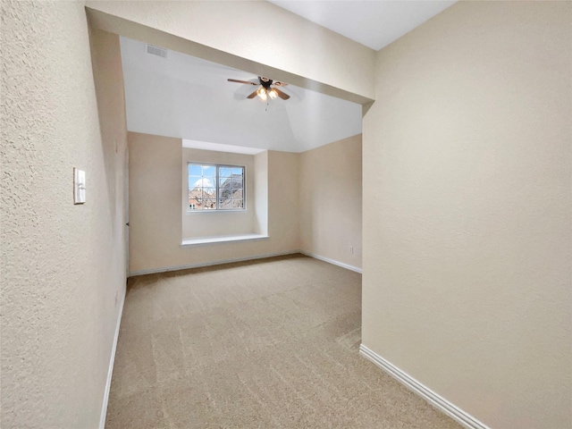 empty room with a textured wall, carpet floors, visible vents, baseboards, and a ceiling fan