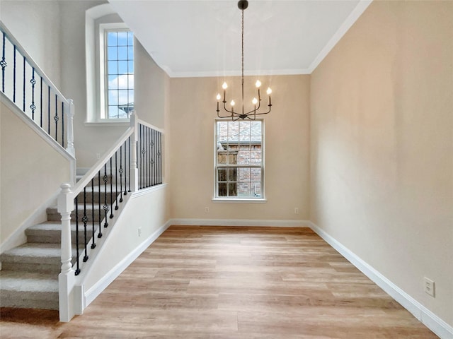 unfurnished dining area with baseboards, stairway, ornamental molding, light wood-style floors, and a notable chandelier