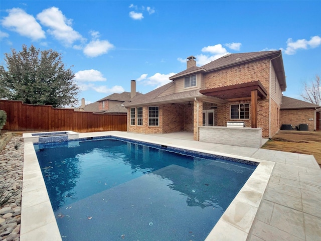 view of swimming pool with a patio area, a fenced backyard, a pool with connected hot tub, and outdoor dry bar