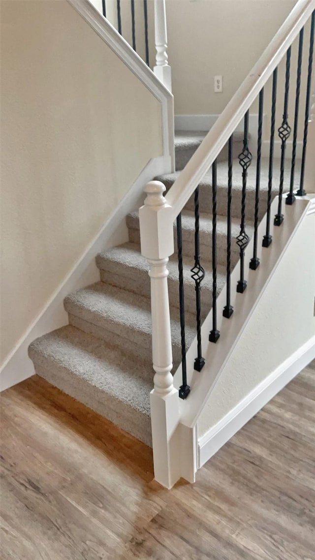 staircase featuring wood finished floors and baseboards