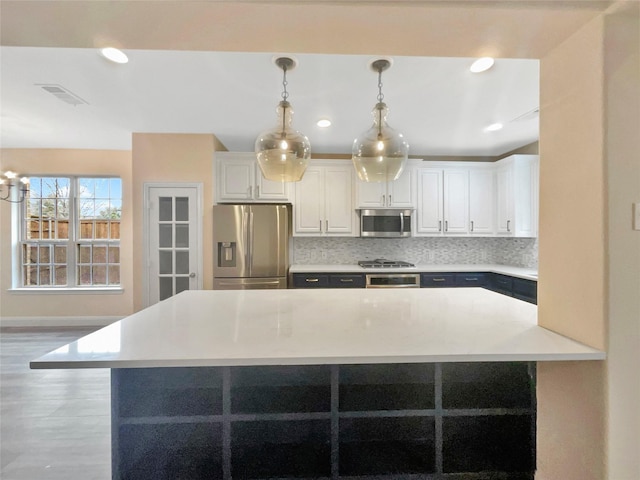 kitchen with white cabinetry, visible vents, light countertops, appliances with stainless steel finishes, and decorative backsplash