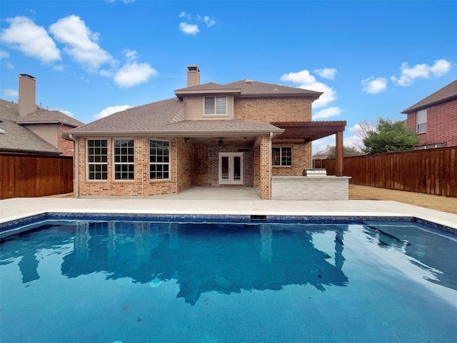 view of swimming pool with a fenced in pool, french doors, a patio, outdoor dry bar, and a fenced backyard