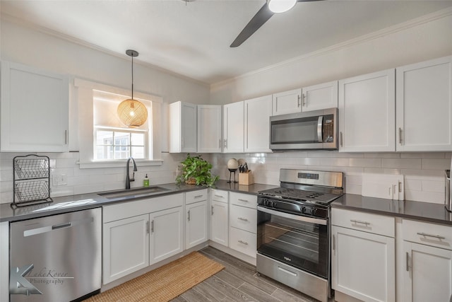 kitchen with appliances with stainless steel finishes, backsplash, dark countertops, and a sink