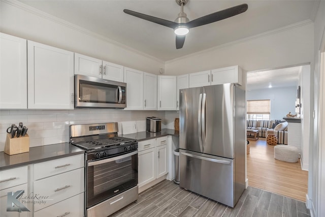 kitchen featuring stainless steel appliances, wood finish floors, dark countertops, and tasteful backsplash