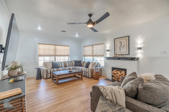 living room with visible vents, baseboards, a ceiling fan, wood finished floors, and a brick fireplace