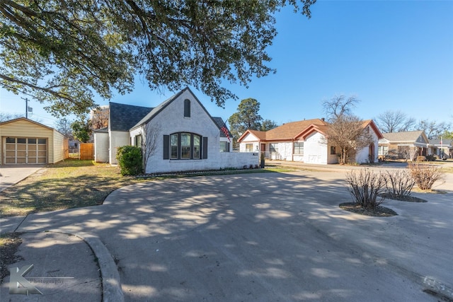 french country home featuring a detached garage, concrete driveway, and an outdoor structure