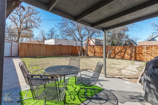 view of patio featuring a storage unit, outdoor dining space, an outdoor structure, and a fenced backyard