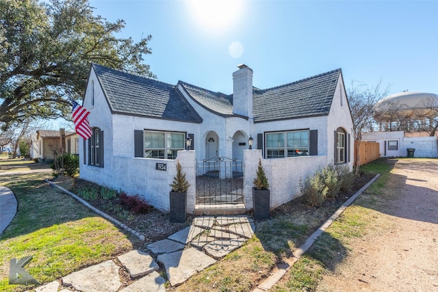 view of front of house featuring a fenced front yard, a gate, and a chimney