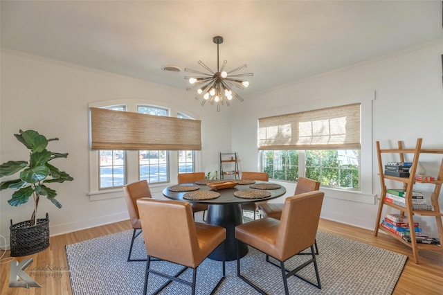 dining room featuring a healthy amount of sunlight, a notable chandelier, and light wood-style flooring