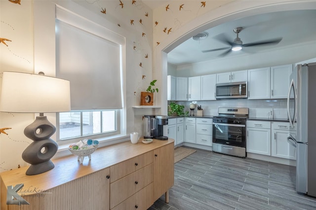 kitchen with visible vents, a ceiling fan, appliances with stainless steel finishes, wood tiled floor, and backsplash