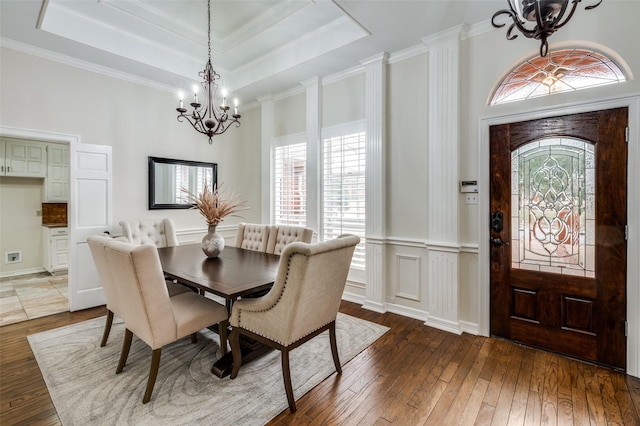 dining room with crown molding, a raised ceiling, a notable chandelier, and wood-type flooring