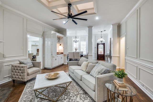 living room featuring dark wood-style floors, crown molding, a decorative wall, coffered ceiling, and ceiling fan with notable chandelier