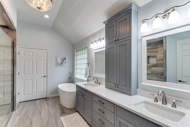 bathroom featuring a freestanding tub, vaulted ceiling, a sink, and a shower stall