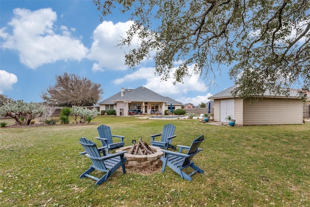 view of yard with an outbuilding, fence, a fire pit, and a shed