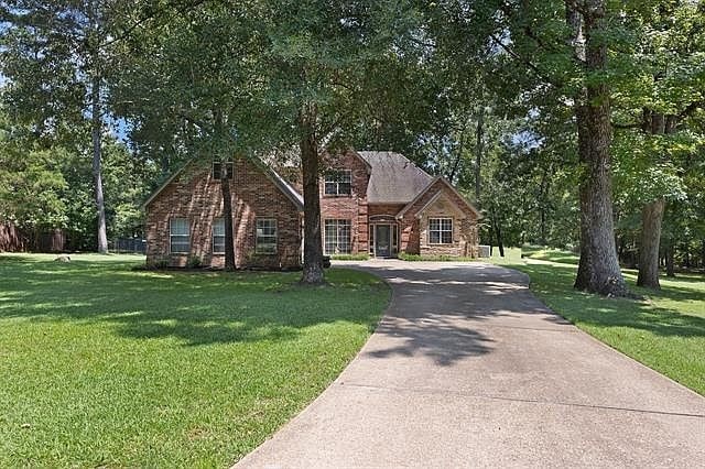 view of front of house featuring driveway, brick siding, and a front yard