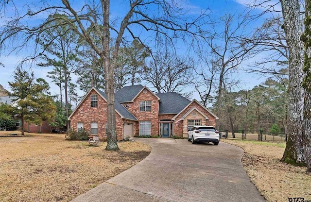 view of front of property featuring concrete driveway, brick siding, roof with shingles, and fence