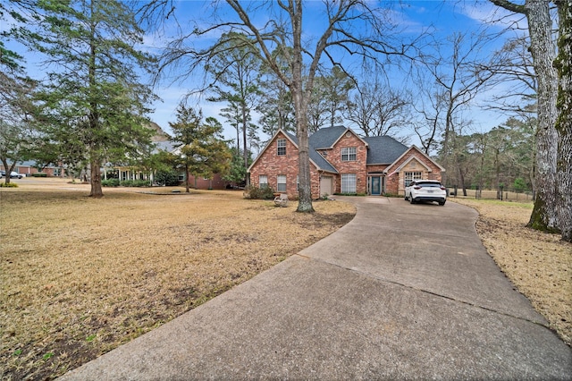 view of front of house with a front yard, concrete driveway, and brick siding